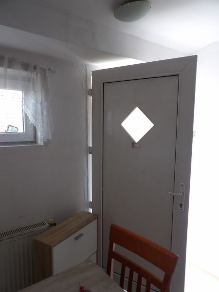 The entrance door in a 2-room apartment with a wooden decor of the dresser and chair.