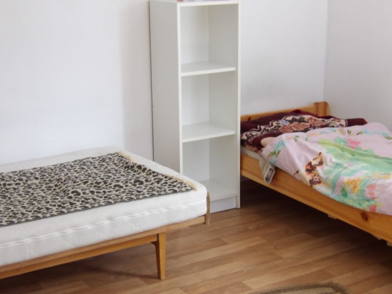 Two beds, a shelf, and a floor with a wooden decor in a 2-room apartment.