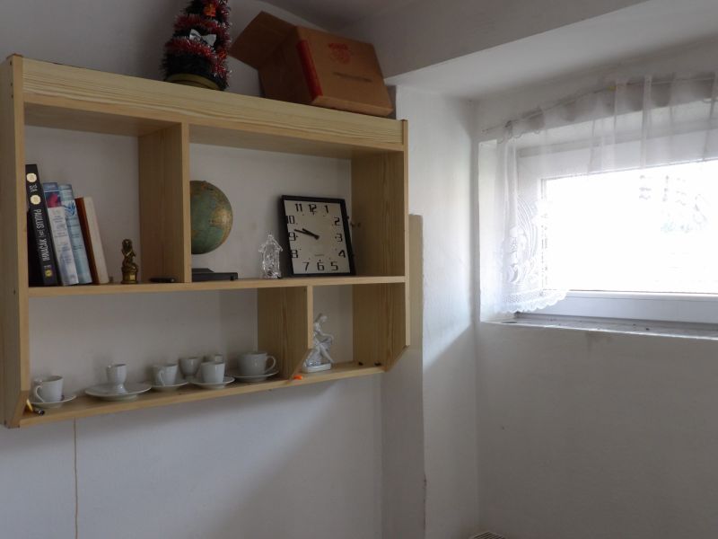 A shelf with souvenirs and books in a 2-room apartment with light from the window.
