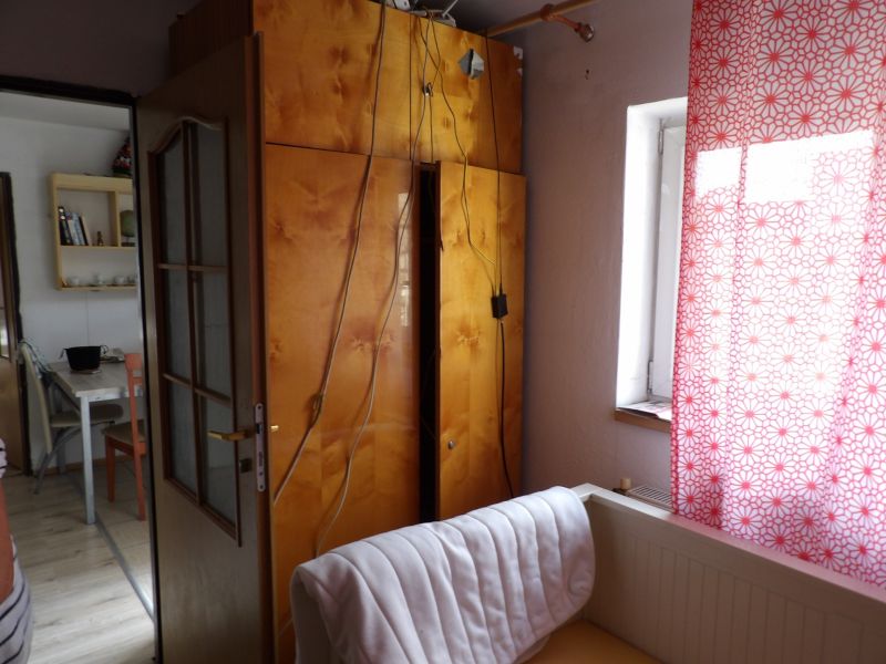 A room in a 2-room apartment with open doors, a cabinet, and a curtain with a red pattern.