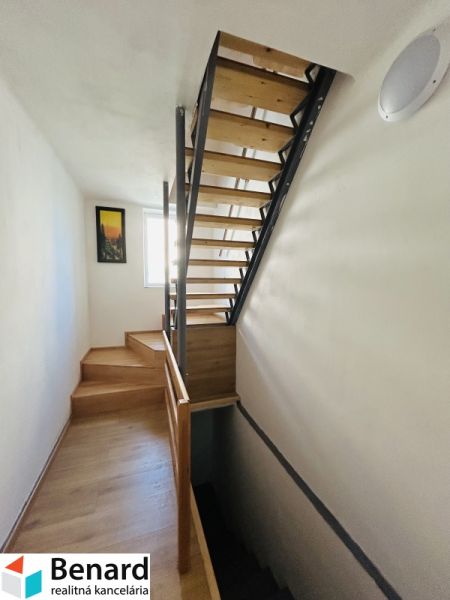 A staircase with a wooden decor in a family house with a bright interior and a painting on the wall.