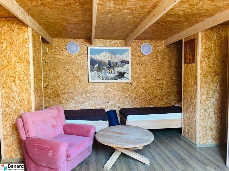 A room in a family house with two beds, a pink armchair, and a wooden-patterned floor.