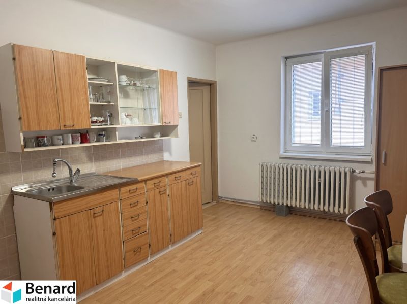 A kitchen with a wooden cabinet and a floor with a wood design in a family house.