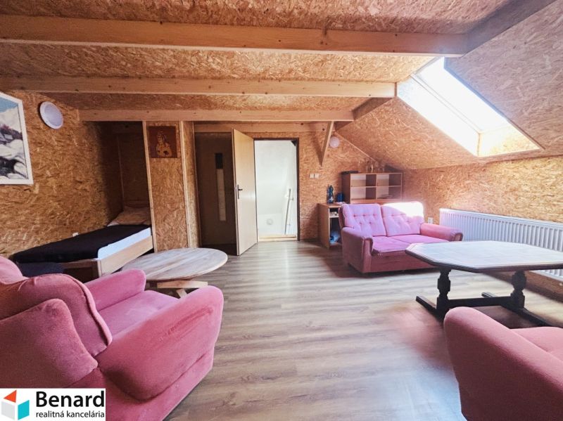 Attic room in a family house with pink furniture and a wooden decor floor.