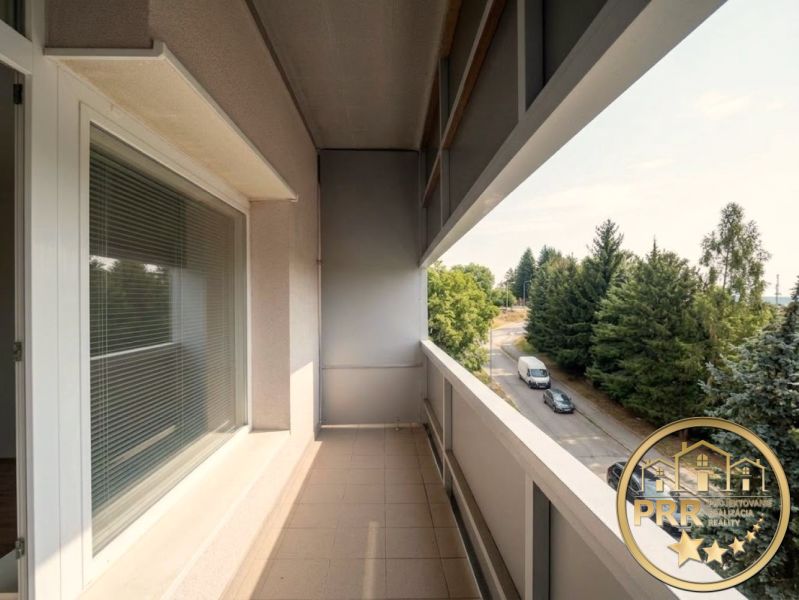 Balcony of a 2-room apartment in Bánovce nad Bebravou with a view of the road and trees.
