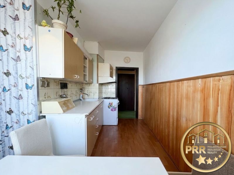 A kitchen in a 2-room apartment with a wooden floor decor and white cabinets.