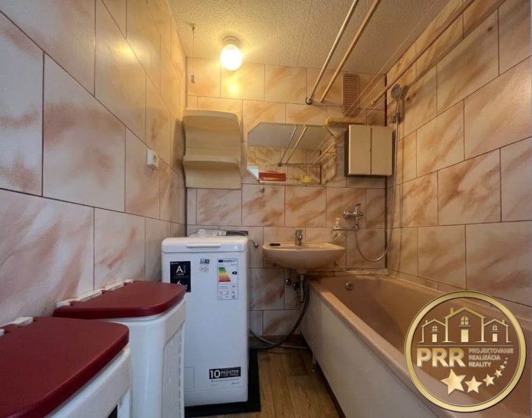 Bathroom in a 2-room apartment with a bathtub, sink, washing machine, and tiles.