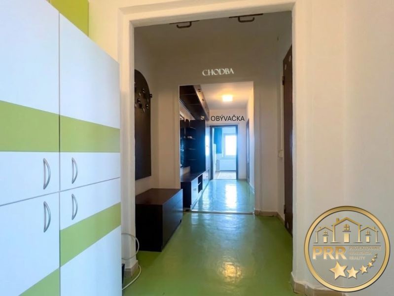 A hallway in a 2-room apartment with a green floor and furniture with white and green elements.