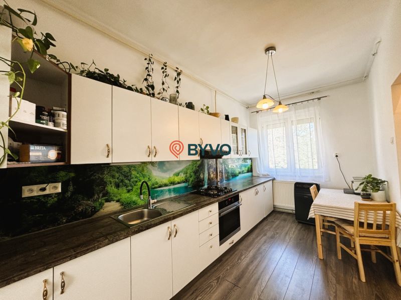A kitchen with a wooden decor countertop, table, and floor in a two-room apartment.