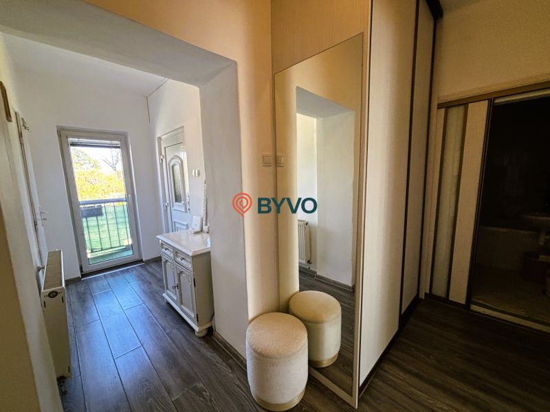The entrance hall in a 2-room apartment with a mirror and a wooden decor floor.