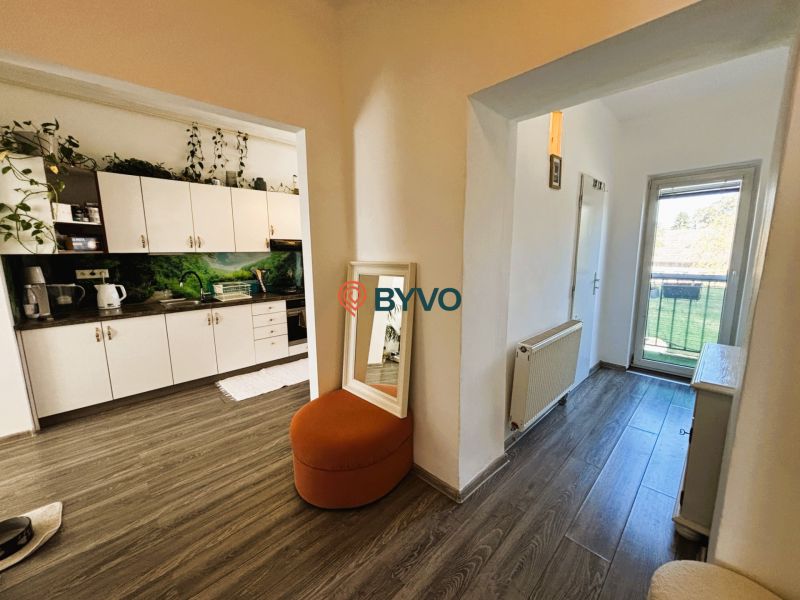 Interior with a kitchen unit, wooden decor flooring, and balcony doors in a 2-room apartment.