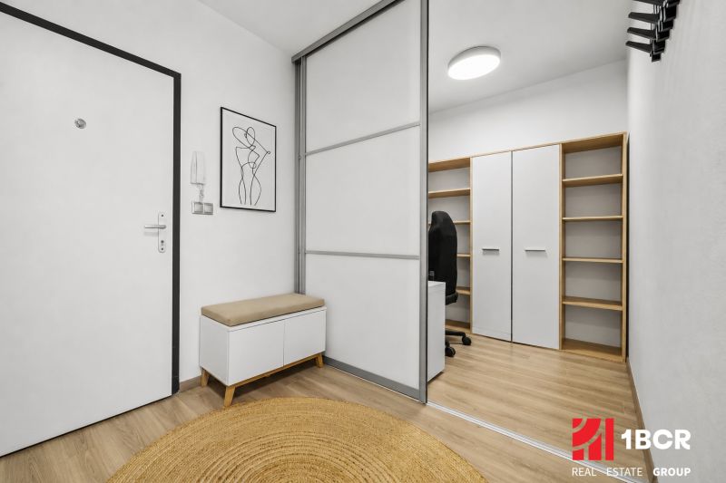 Hallway with a white wardrobe, bench, decoration, and wooden decor flooring in a 2-room apartment.