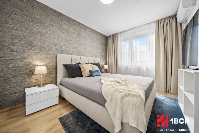 Bedroom with a bed and a nightstand, wooden decor flooring in a 2-room apartment.