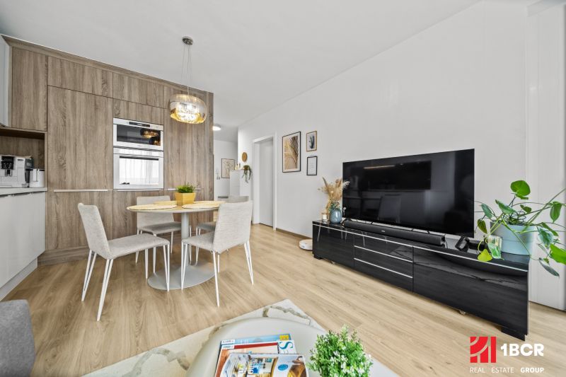 Living room and kitchen in a two-room apartment with a wooden decor floor.