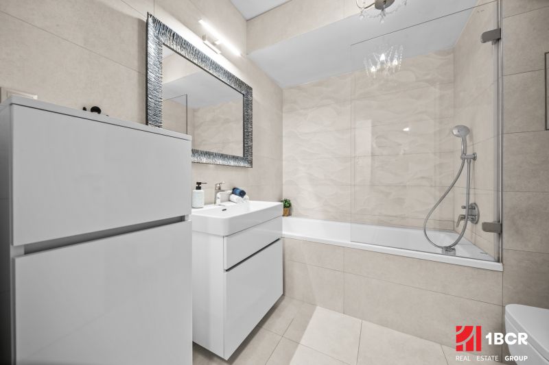 Bathroom in a 2-room apartment with a shower and a bathtub, light tiles.