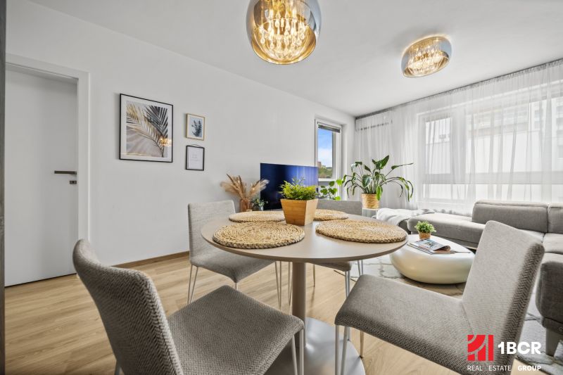 Interior of a 2-room apartment with a dining area, wooden decor flooring, and an elegant chandelier.