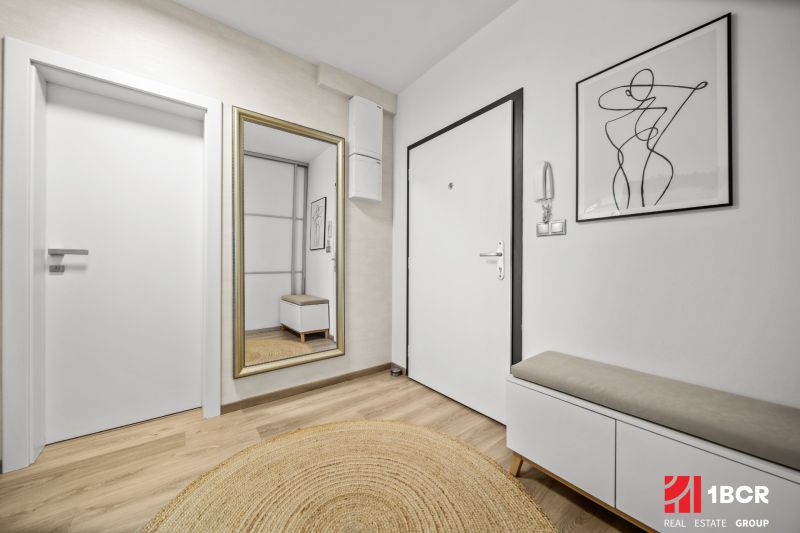 Entrance hall in a 2-room apartment with a wooden decor floor and a mirror.