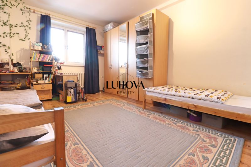 A bedroom with a large bed, wardrobe, carpet, and wood-patterned flooring in a 2-room apartment.