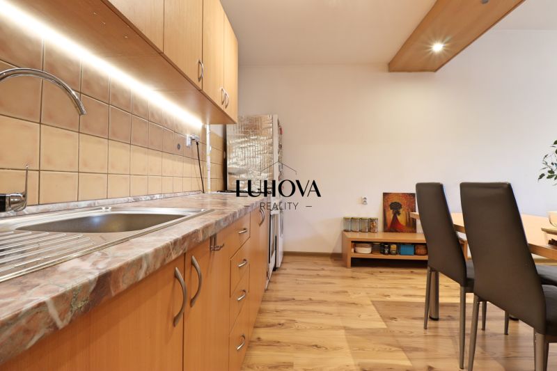 A kitchen in a 2-room apartment with wooden floor decor and wooden cabinets.