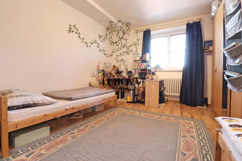 Children's room in a 2-room apartment with a bed, table, and wooden floor decor.