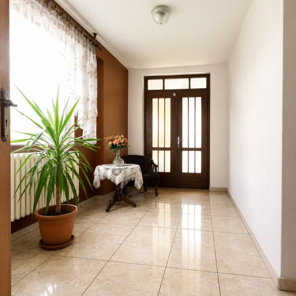 Interior of a family house with ceramics, a plant, a table, and an upholstered armchair.