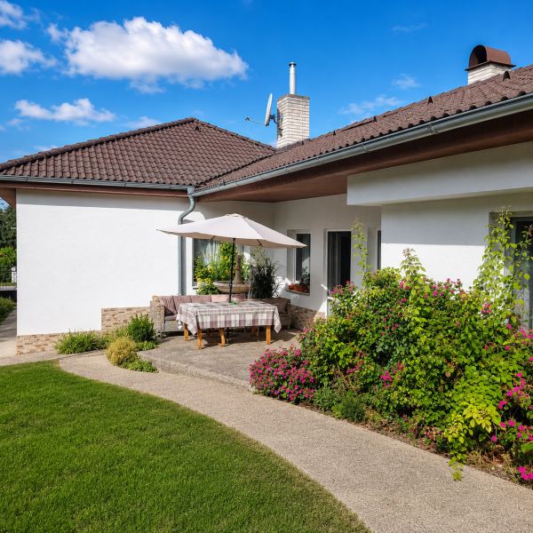A family house in Šalgočka with a terrace, garden, and a sunshade on a grassy plot.
