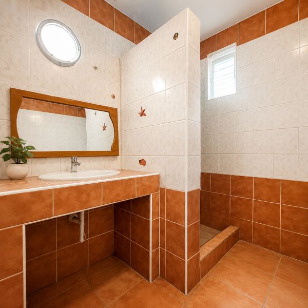 A bathroom in a family house with ceramic tiles and a wooden mirror.