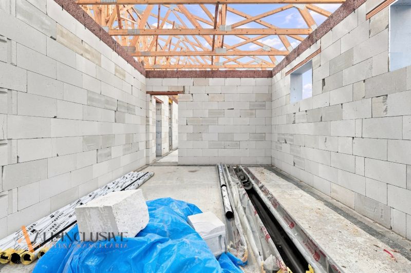 An unfinished family house in Marcelová with visible walls and a roof made of wooden beams.