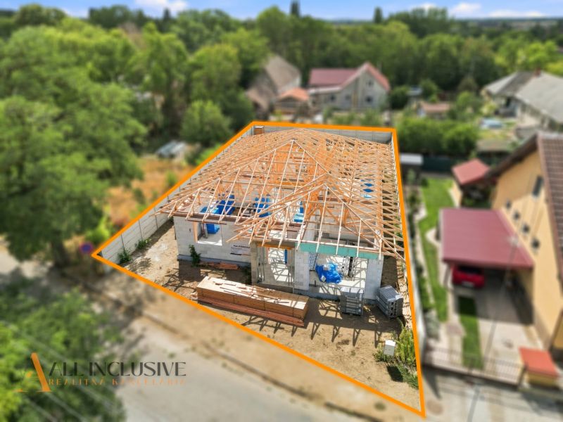 A family house in Marcelová under construction, surrounding houses and greenery in the background.