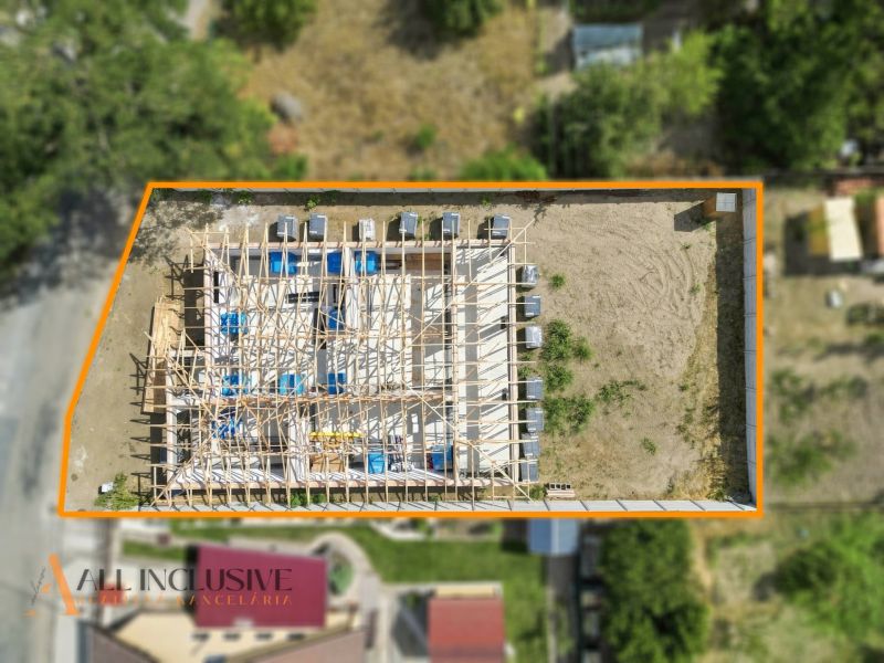 A family house construction in Marcelová from above, surrounded by an orange frame, encircled by greenery.
