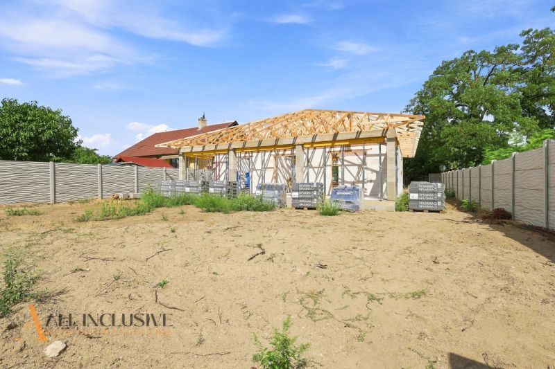 An unfinished family house in Marcelová with fencing, standing on an empty plot with grass.
