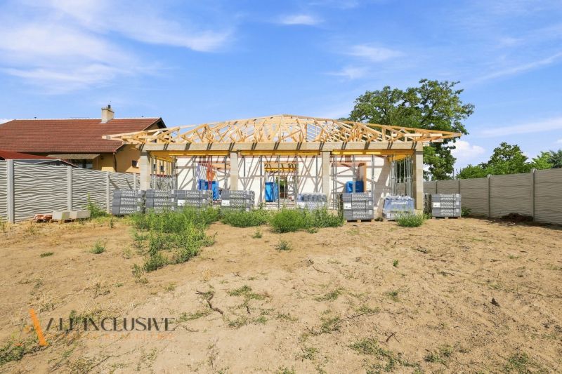 Construction of a family house in Marcelová with a roof under construction and fencing.