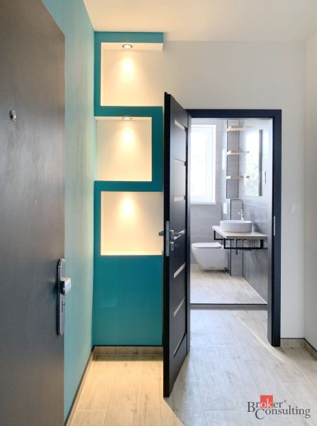 Interior of a 1-room apartment with a wooden decor floor and a modern bathroom.