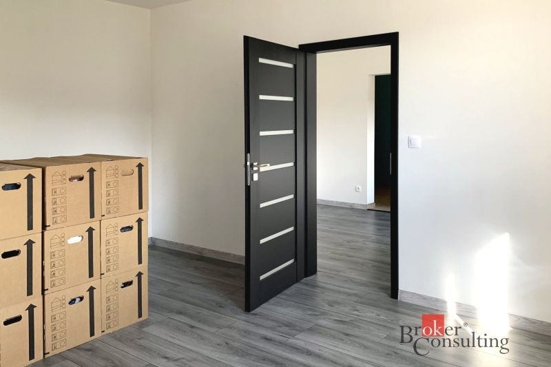 A one-room apartment with a wooden decor floor and boxes in the room.