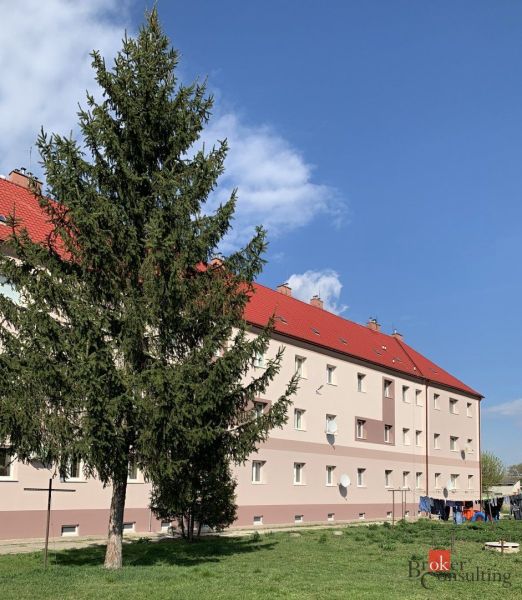 A building with red roofs and a tree in front of it, on Železničná Street in Šahy.