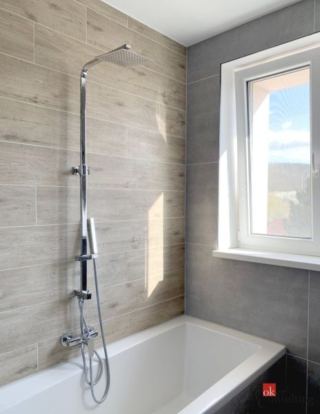 Bathroom with a bathtub and shower, wood decor tiles, large window, studio apartment.
