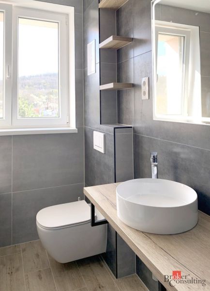 A bathroom in a studio apartment with a sink and a floor with a wood design.