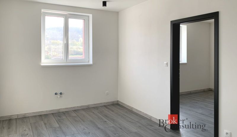 The interior of a one-room apartment with a wooden decor floor and white walls.