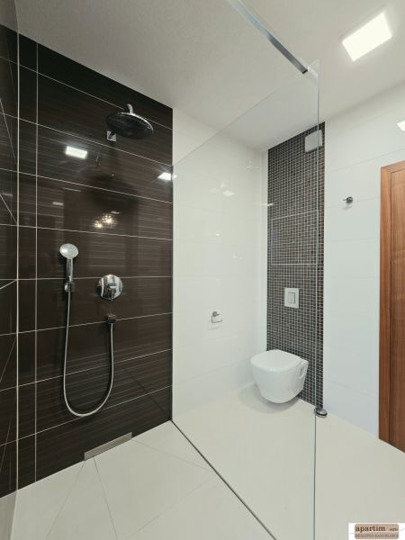 Bathroom with a shower and wall-mounted toilet in a 4-room apartment.