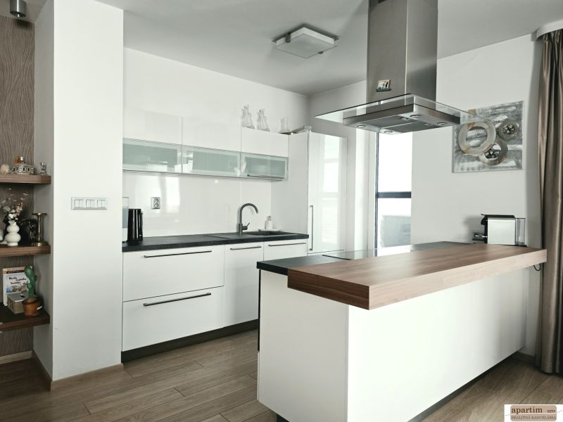 A kitchen in a 4-room apartment with a kitchen unit and an island, flooring with a wooden decor.