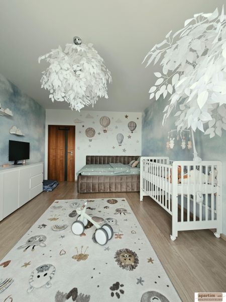 Children's room in a 4-room apartment with a crib, decorative carpet, and wooden-patterned flooring.