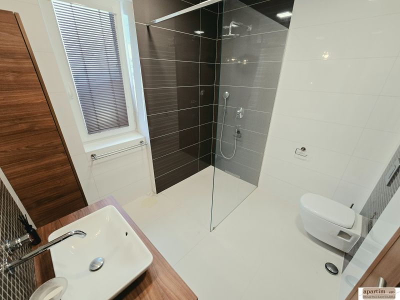 Bathroom in a 4-room apartment with a sink, shower, and dark tiles.