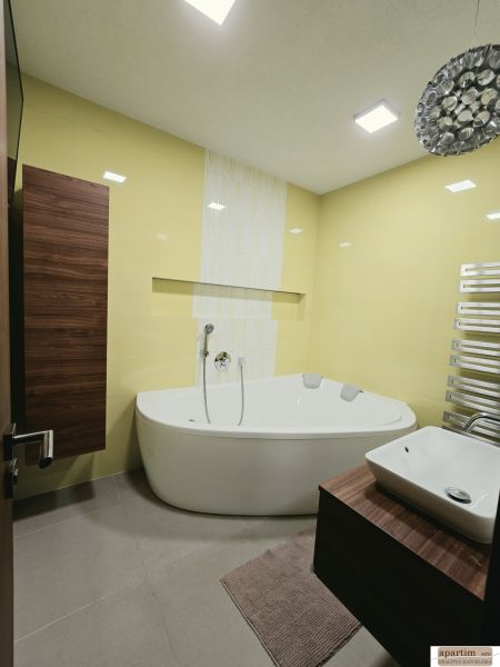 A bathroom with yellow tiles, a corner bathtub, and a wooden cabinet decor in a 4-room apartment.
