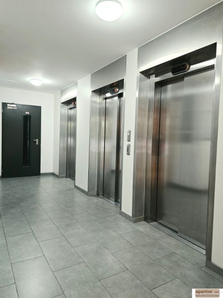 A hallway with four metal elevators and gray tiles in a 4-room apartment.