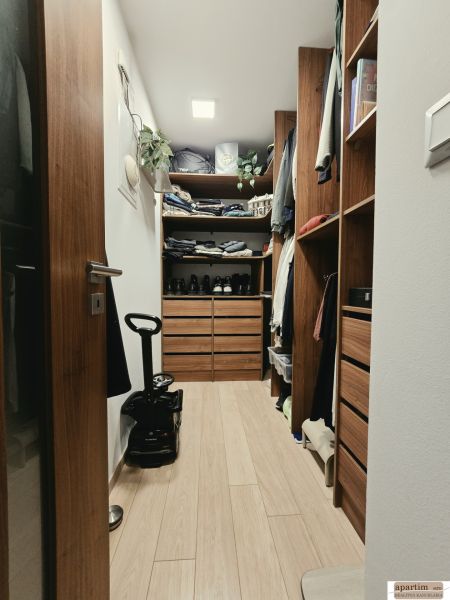A wardrobe with cabinets and shelves in a 4-room apartment with a wood-decor floor.