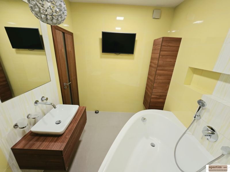 A bathroom with light yellow walls, a bathtub, a sink, and a mirror in a four-room apartment.