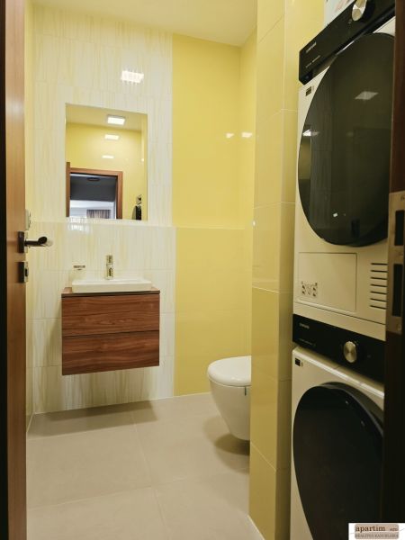 Bathroom in a 4-room apartment, light yellow tiles, sink, toilet, washing machine, and dryer.