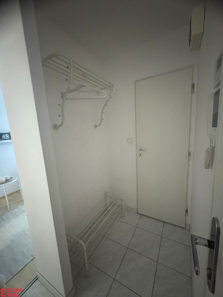 Entrance hall with a coat rack and shoe cabinet in a studio apartment with tiled flooring.