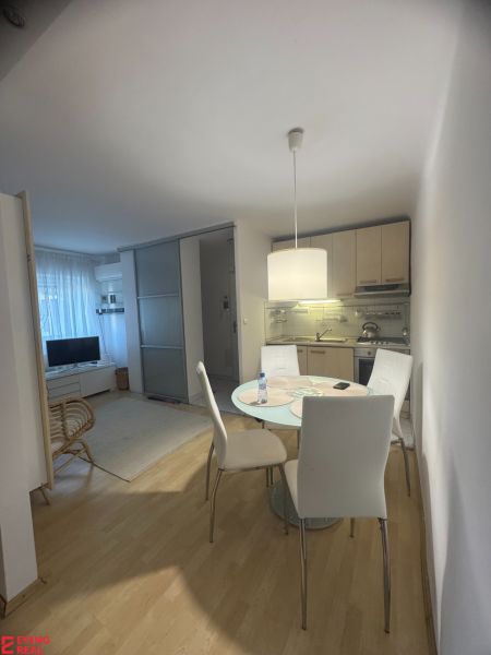 Dining area in a studio apartment with a kitchen and a wooden decor floor.