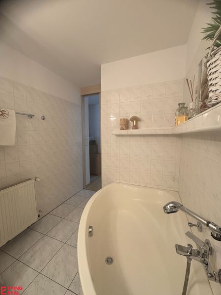 Bathroom in a studio apartment with a bathtub, ceramic tiles, and decorations.